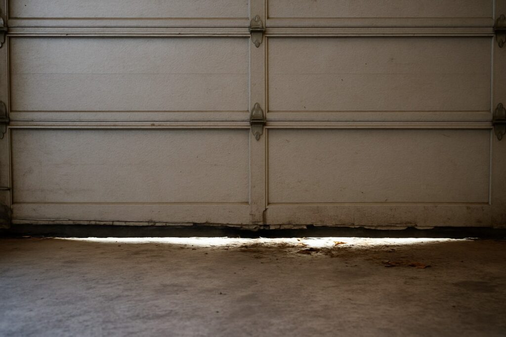 Houston, TX Garage Door Maintenance: Keep Your Garage Doors Safe and Efficient 3 Garage Door Maintenance showing a worn and inefficient bottom seal with visible light gaps, indicating poor insulation and the need for repair.